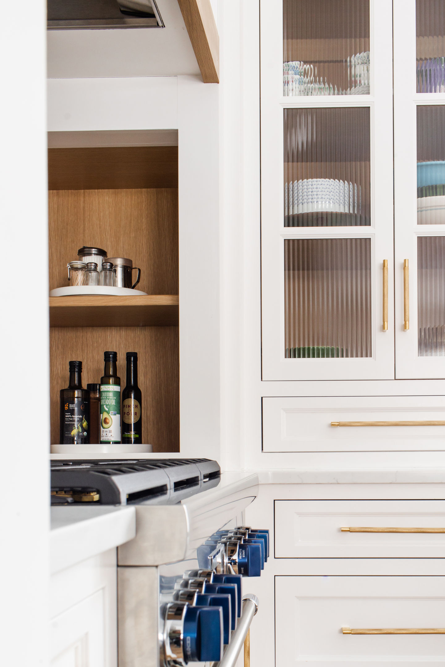 Edina Minnesota custom home interior remodel featuring custom white painted cabinets, Sherwin Williams cyberspace painted island, gold hardware, custom lighting, luxury cabinets, black bar stools, Andersen black windows, Delta faucet, Thermador kitchen range, and white oak accents