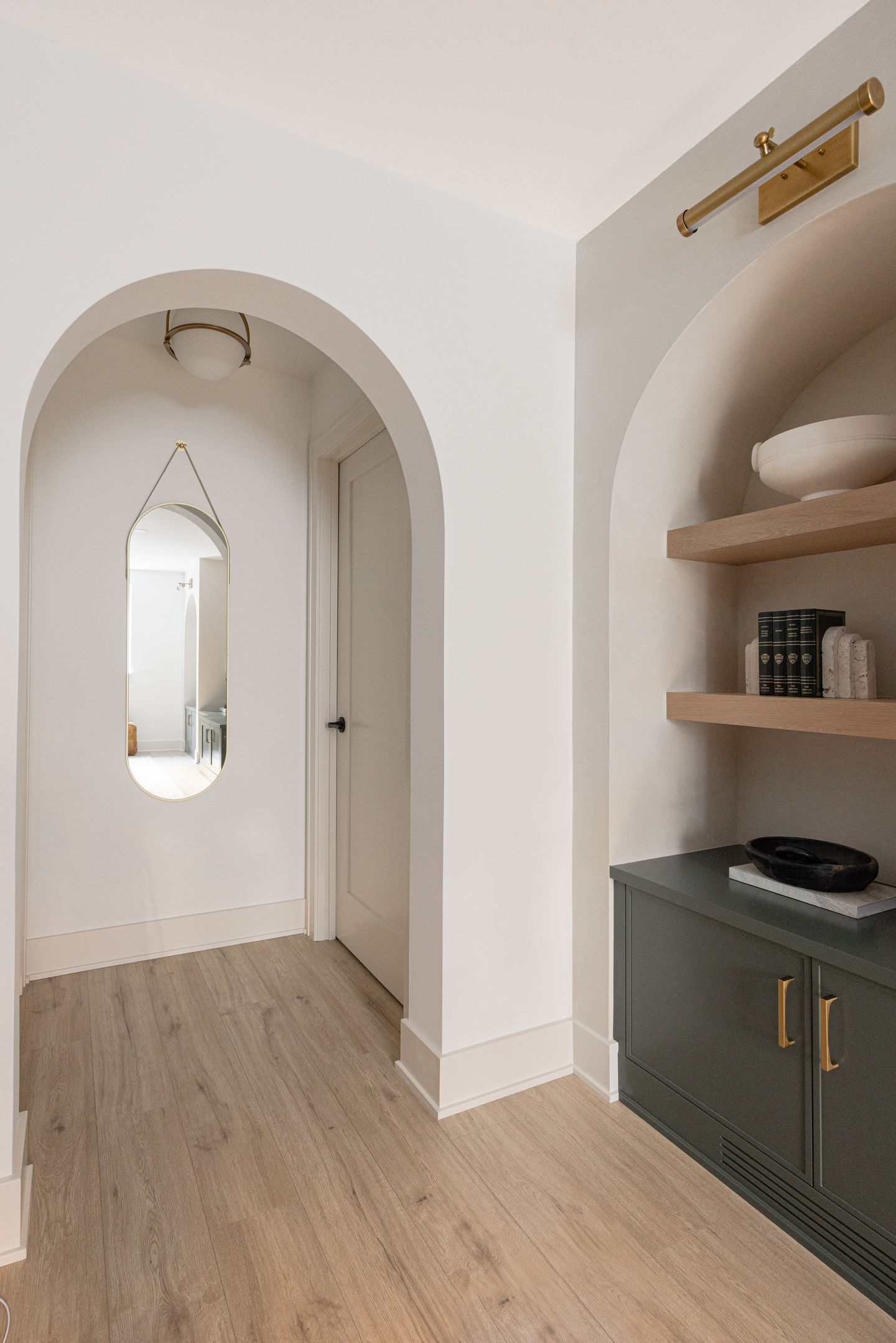 arched doorway next to a tan plaster accent wall with pewter green cabinets