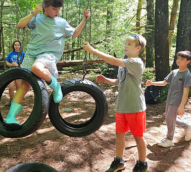 Children at Camp HLC playing on tire swings