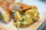 Croissant sandwich filled with creamy chicken salad and herbs on a wooden board.