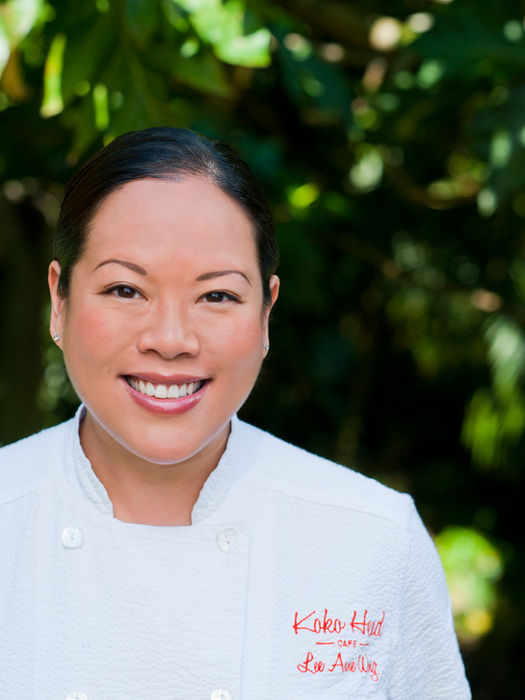 Smiling female chef in a white uniform outdoors.