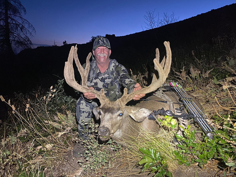 a guy posing with an elk he just harvested from the wilderness