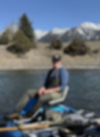 Noble Vance, owner of Western Log & Timber, fly fishing on a Montana river with mountain scenery in the background.