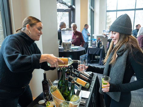 Woman pouring wine for a guest at a tasting event.