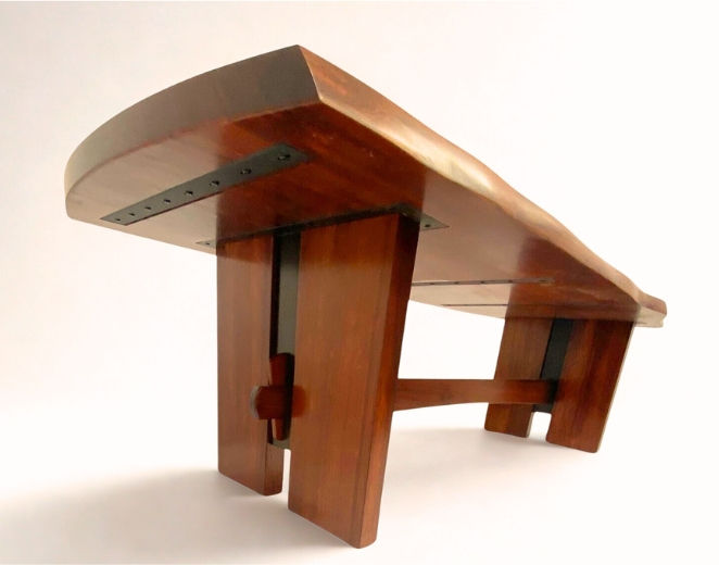 Underside view of live-edge redwood dining table showing trestle base and exposed joinery.