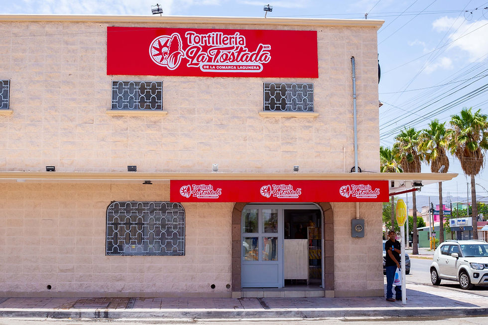 Foto de la sucursal Tortillería La Tostada con fachada color beige y toldos rojos con el logotipo, formato horizontal wide landscape.