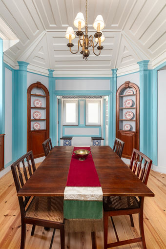 Vista ampla da sala de jantar com painéis de teto em madeira restaurados, nichos embutidos em madeira e soalho em pinho. Obra realizada pelo Atelier Bustorff na casa paroquial da Igreja de São Sebastião, em Lisboa.
