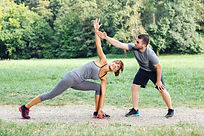 Man helping woman with yoga pose