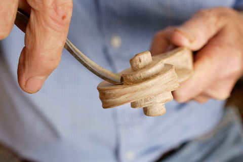 A detail image of an artisan handcrafting violins from wood.
