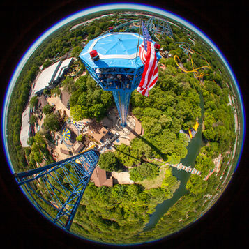 An aerial fisheye view of workers on the top of a tall theme park rollercoaster