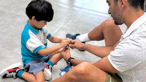 Niño pequeño y adulto compartiendo un momento de aprendizaje juntos en el suelo del aula en el preescolar ABCnMe en Costa del Este, Panamá, fortaleciendo vínculos y habilidades socioemocionales.