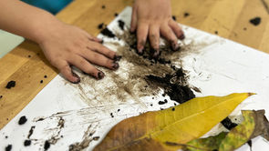 Niño juega con tierra y hojas, con las manos, en el preescolar ABCnMe en Costa del Este, Panamá, obteniendo aprendizaje y estimulación temprana.