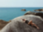 Woman lounging on rocks by the sea, basking in the sun and enjoying nature's beauty Dew. KC Summer Slim Down Special