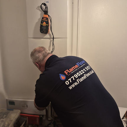 Stevie working beneath a Worcester boiler, with testing equipment visible above him.