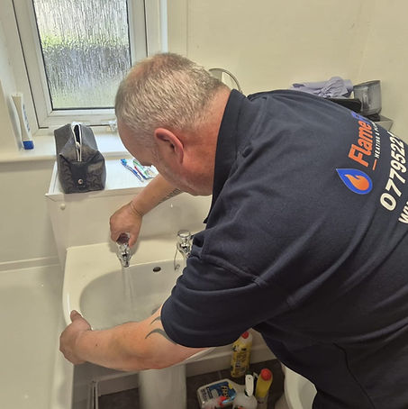 Stevie checking a bathroom basin tap in his FlameFlow uniform.