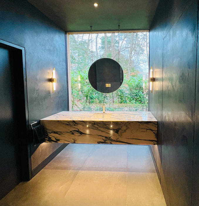 Modern Bathroom design, polished plaster walls with custom marble vanity floating in front of a floor to ceiling window. Floating circular mirror suspended from the ceiling.