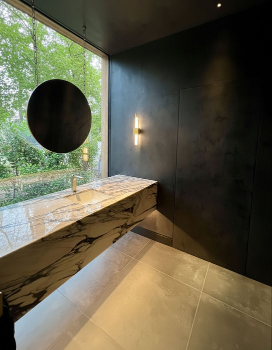 Modern bathroom marble detail, a dramatic powder room, and the Calacatta Viola Marble is an incredible colour to have adjacent to the green boundary foliage outside.