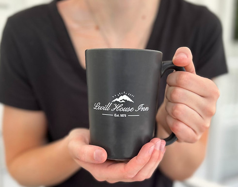 Woman holds coffee mug with Lovill House Inn logo