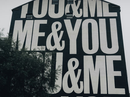 Side of building painted black and white reading "You & Me...Me & You" to symbolize authentic community 