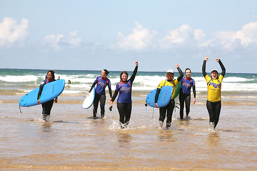 Cornwall women only surf yoga retreat's surf instructors and guests walking up the beach after a beginner surf lesson.