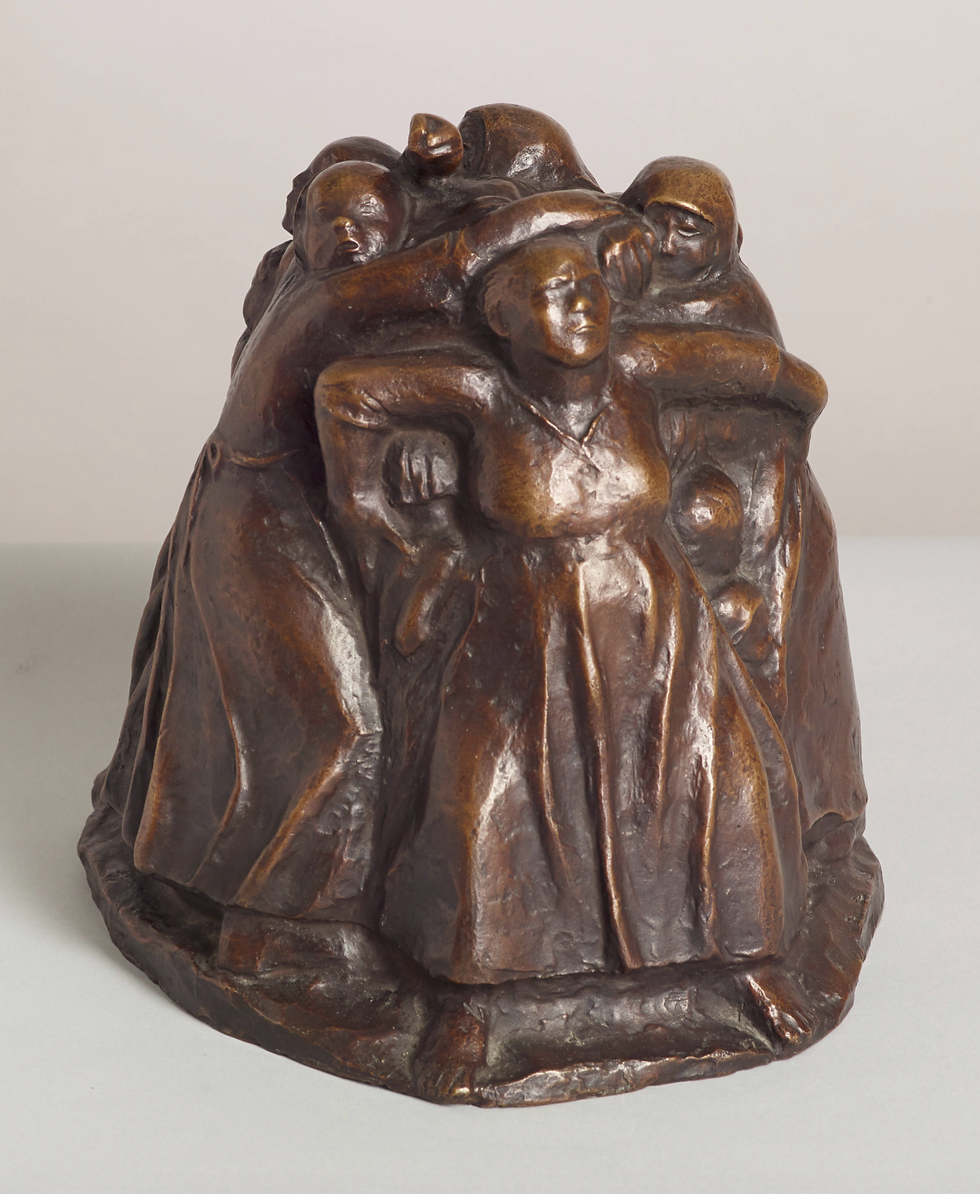 Bronze sculpture of four bundled figures huddled together in a group embrace on a plain light background.