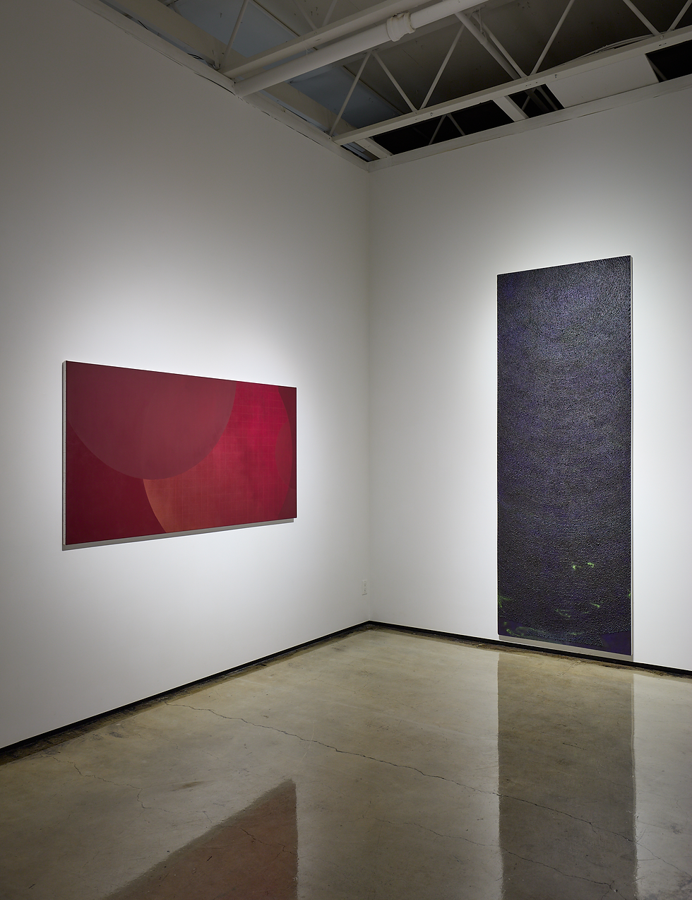 Minimal gallery corner with two abstract paintings: a red square on left and a tall dark textured piece on right, under exposed beams.