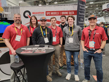 Quantum Land Design team at ConExpo-Con/AGG booth, promoting GPS models and drone data solutions for earthmoving and construction technology ahead of ConExpo 2026.
