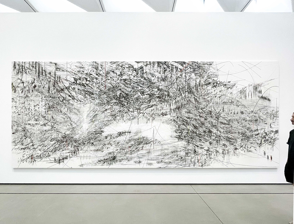 Museum wall with a large black-and-white abstract drawing; a person stands at the right edge, viewing it in a bright gallery.