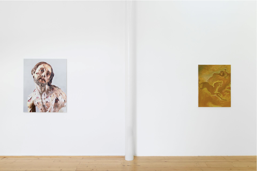 Two portrait artworks hang on a white gallery wall with a central pillar and wooden floor; one shows a worried man, one golden abstract figure