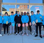 Male students from Waterloo Career Center painting festive holiday designs on downtown Waterloo storefront windows.