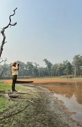 Mamma con binocolo impegnata nel birdwatching nel Chitwan National Park, immersa tra suoni e colori della giungla nepalese.