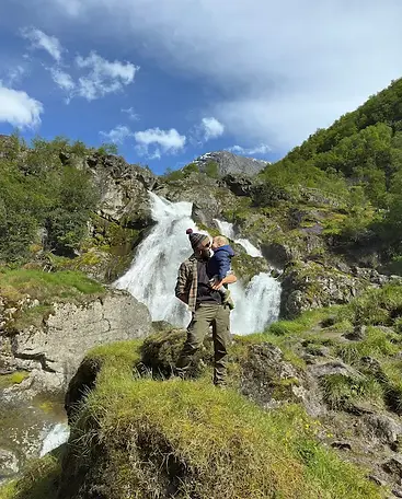 Mattia Melegari e figlio davanti a una piccola cascata durante il trekking verso il ghiacciaio Briksdalsbreen, tra rocce, muschio e il respiro autentico dei viaggi in famiglia nella natura norvegese.