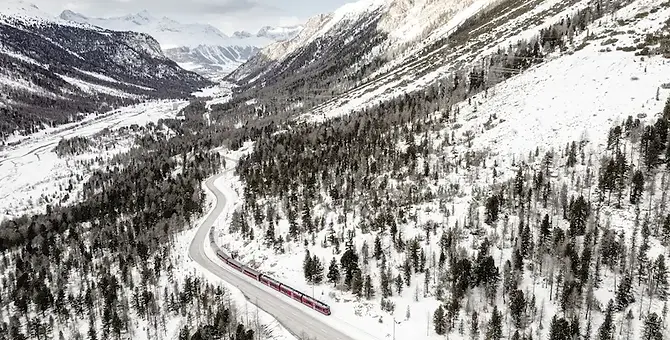 Treno del Bernina in corsa sulla linea ferroviaria tra le montagne innevate