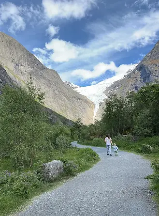 Mamma e bambino camminano insieme sul sentiero verso il ghiacciaio Briksdalsbreen, tra natura selvaggia e scoperta familiare.