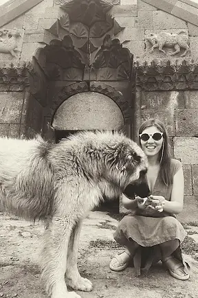 Mamma con un pastore caucasico, cane tradizionale della regione, davanti al caravanserraglio di Orbelian, uno storico punto di sosta lungo le rotte commerciali.