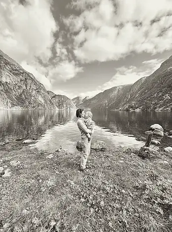 Mamma che bacia il figlio davanti a un fiordo norvegese, un gesto d’amore che racchiude la magia dei viaggi in famiglia nella natura del Nord.