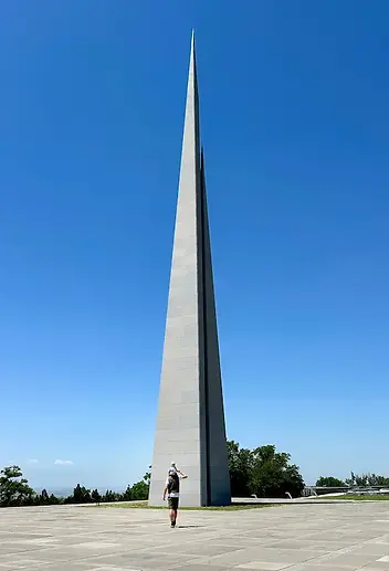 Papà con figlio sulle spalle al Monumento del Genocidio Armeno di Yerevan, con la maestosa struttura commemorativa.