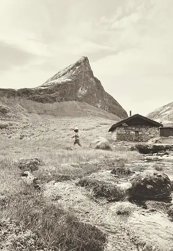 Bambino che corre felice a Herdalssetra, tra montagne e cascata, immerso nella natura della Norvegia durante un viaggio con bambini.