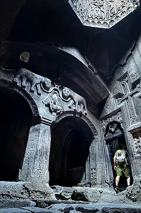 Papà con bambino nella fascia in esplorazione archeologica al Monastero di Geghard, uno dei siti spirituali più significativi dell'Armenia.