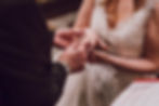 Hombre coloca anillo en mano de mujer con vestido de encaje blanco. Ambiente romántico y solemne. Enfoque en las manos.