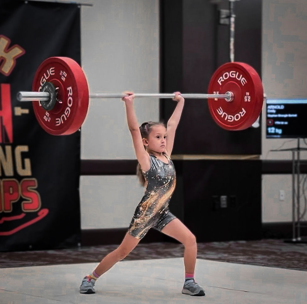 Young girl lifting a barbell in competition, wearing a patterned leotard. Red weights read "ROGUE." Focused, determined expression.