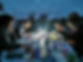 A group of adults sitting around the table at dusk with a low light doing drawing
