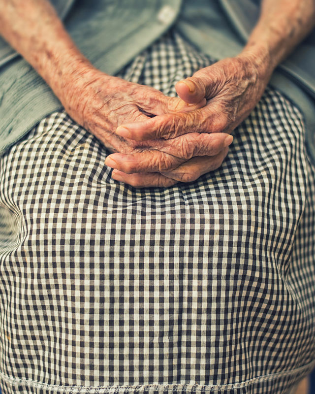Der Schoß einer älteren Dame, ihre Hände sanft gefaltet und ruhend – ein Symbol für Ruhe, Weisheit und gelebte Geschichten.