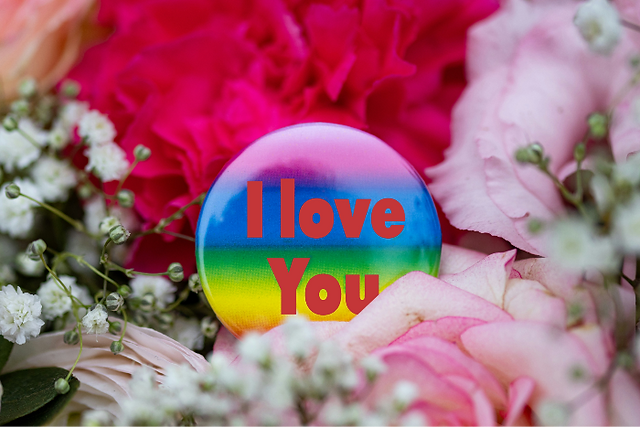 Ein leuchtender Sticker in Regenbogenfarben mit der Aufschrift „I love you“, umgeben von zarten, bunten Blumen, die eine Botschaft der Liebe und Vielfalt symbolisieren.