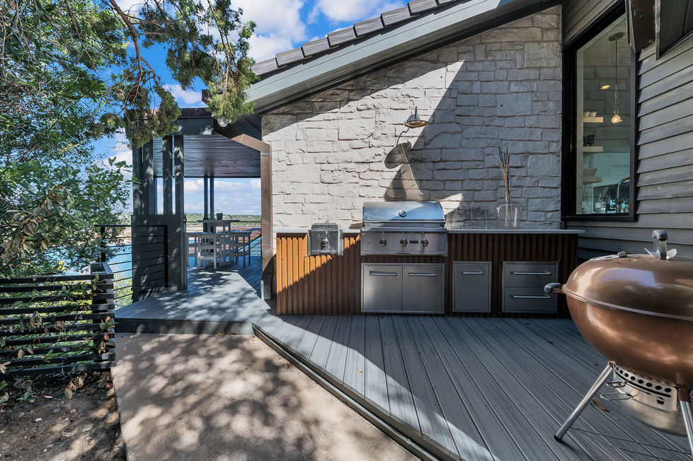 Outdoor BBQ station remodel with built-in stainless grill, custom stonework, and covered deck access in Austin, TX.