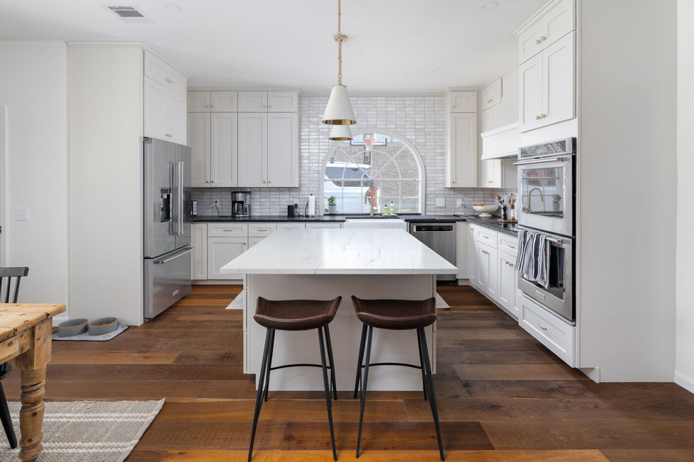 Remodeled transitional kitchen with oversized quartz island, shaker cabinetry, and elegant pendant lighting in an Austin, TX home.