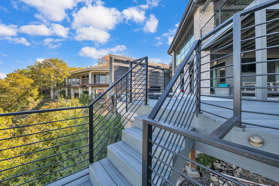 Remodeled exterior staircase with modern cable railing and composite decking, connecting multiple levels of this Lakeway outdoor living space.