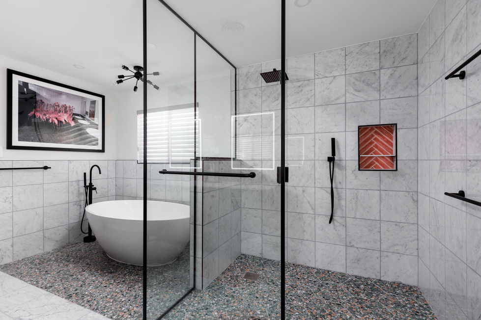Bathroom remodel showcasing terrazzo flooring, freestanding soaking tub, and rain shower against marble tile walls, blending luxury textures and striking design details in Austin, TX.
