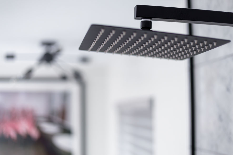 Close-up of a matte black rain showerhead in a modern bathroom remodel, highlighting sleek plumbing details and minimalist interior design in Austin, TX.