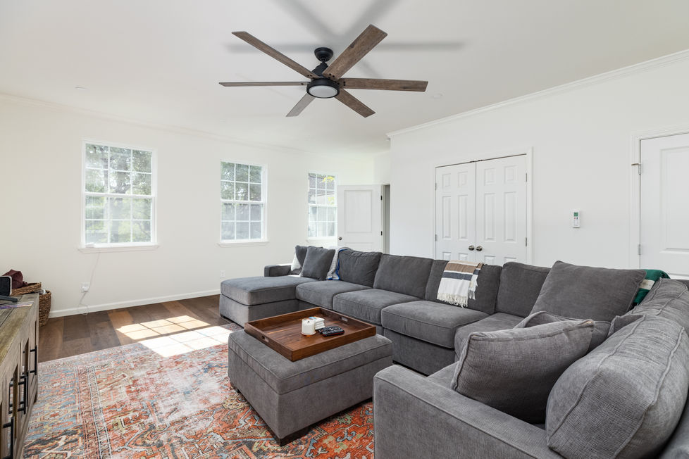 Remodeled family room with cozy modern sectional, vintage Persian-style rug, and a rustic contemporary ceiling fan, designed for a warm and inviting interior in Austin, TX.
